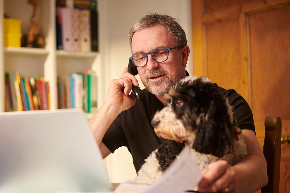 Man working from home on computer while talking on phone