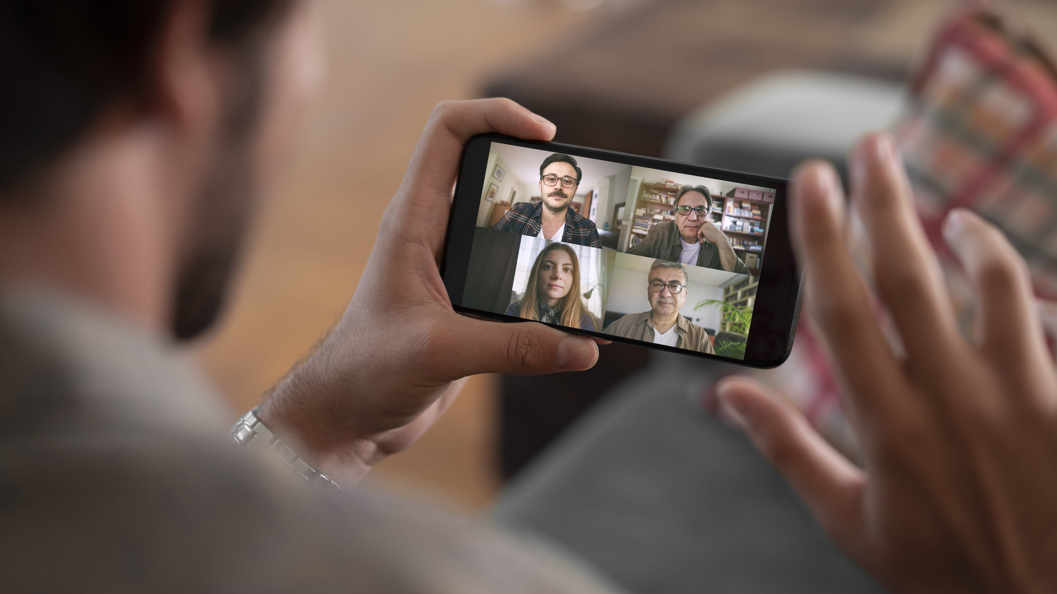 Man holds a mobile phone while on a video call.