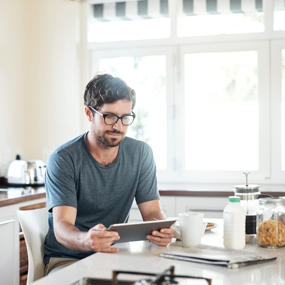 man using a digital tablet while having breakfast